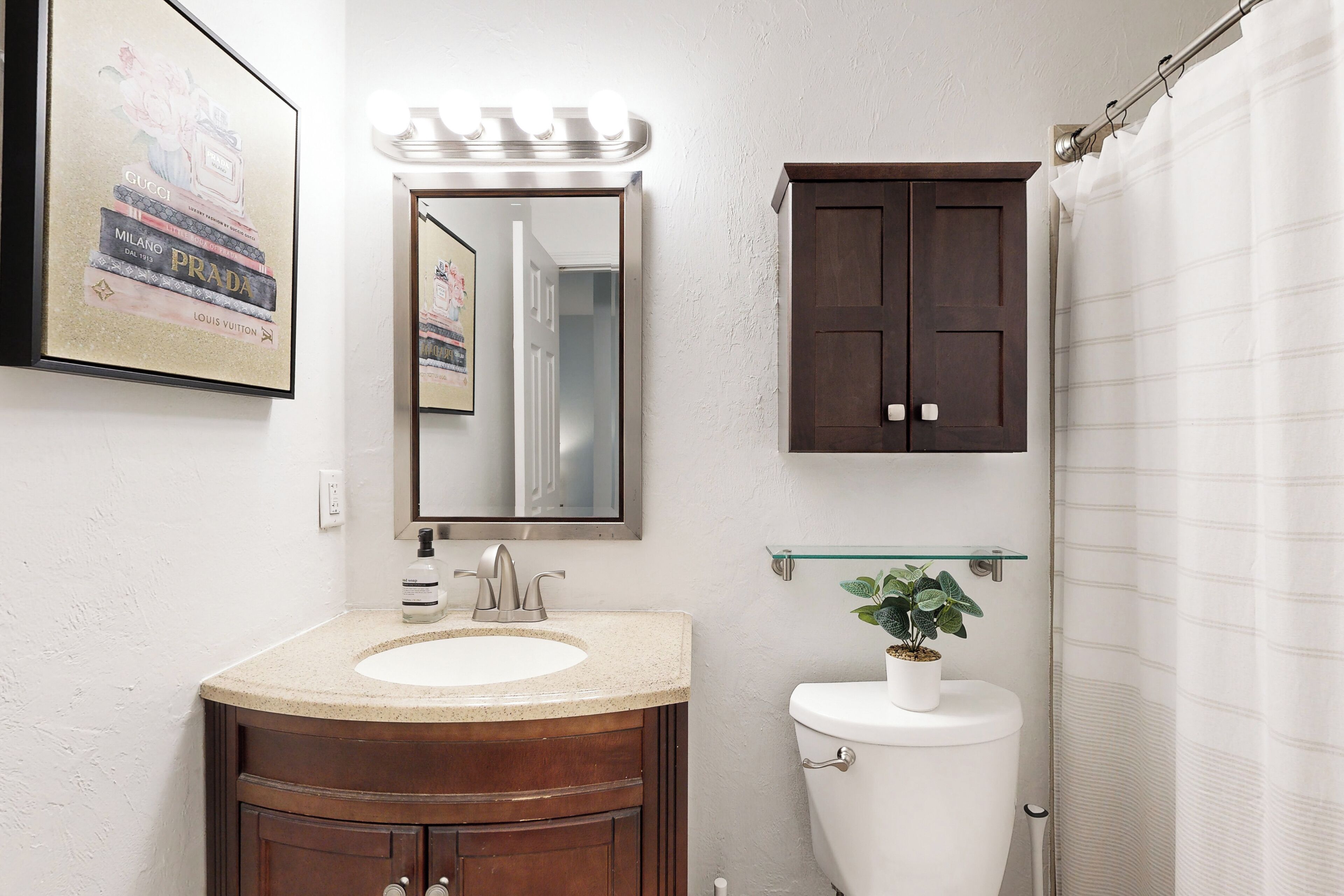 A bathroom with a vanity, sink, mirror, and toilet.