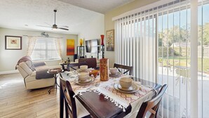 A dining area with a table set for four, a ceiling fan, and a view of the outdoors through large windows. - Dog-friendly Family Home w/ Patio & Fire Pit! (Richmond Hill)