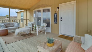 A covered porch with wicker furniture, a welcome sign, and a door with a home doormat.