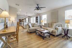 A spacious living room with a wooden floor, a ceiling fan, and a dining area with a table and chairs. - Scenic Sandia Mtn Views! Cozy Rio Rancho Retreat (Rio Rancho)