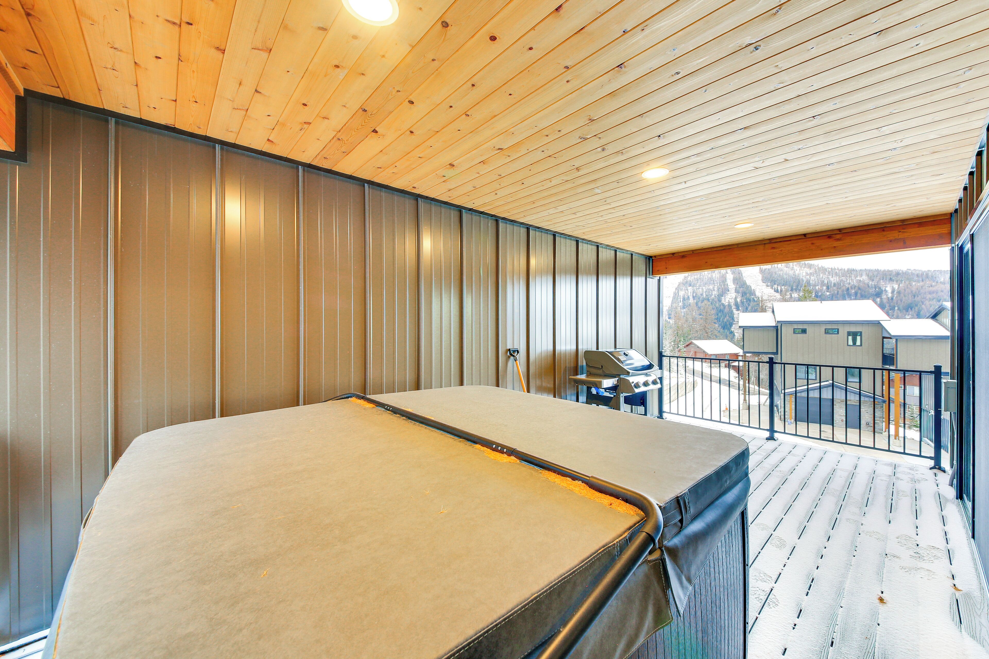 A room with a large bed, a balcony with a view, and a wooden ceiling.