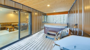 Ein modernes Interieur mit Holzboden, Schiebegläsern zu einem Wohnbereich und einer Whirlwanne.