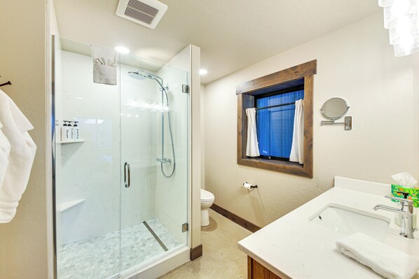 A bathroom with a glass-enclosed shower, a sink with a mirror, and a toilet. - Luxury Ski Home w/ Hot Tub on Schweitzer Mountain (Sandpoint)