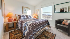 A bedroom with a bed, two bedside tables, a nightstand, a window, a chair, and a ceiling fan. - Mtn Views, 15 Mi to Dtwn Kingman: Family Home! (Kingman)