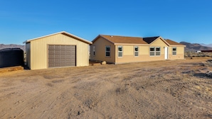 A two-story house with a garage and a detached shed, set in a dry, hilly landscape. - Mtn Views, 15 Mi to Dtwn Kingman: Family Home! (Kingman)
