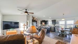A spacious living room with a large TV, comfortable seating, a ceiling fan, and a view of the kitchen and dining area. - Mtn Views, 15 Mi to Dtwn Kingman: Family Home! (Kingman)
