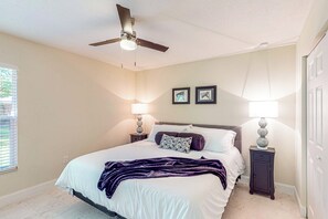 Ein Schlafzimmer mit einem Bett, zwei Nachttischlampen, einem Deckenventilator und zwei gerahmten Bildern an der Wand.