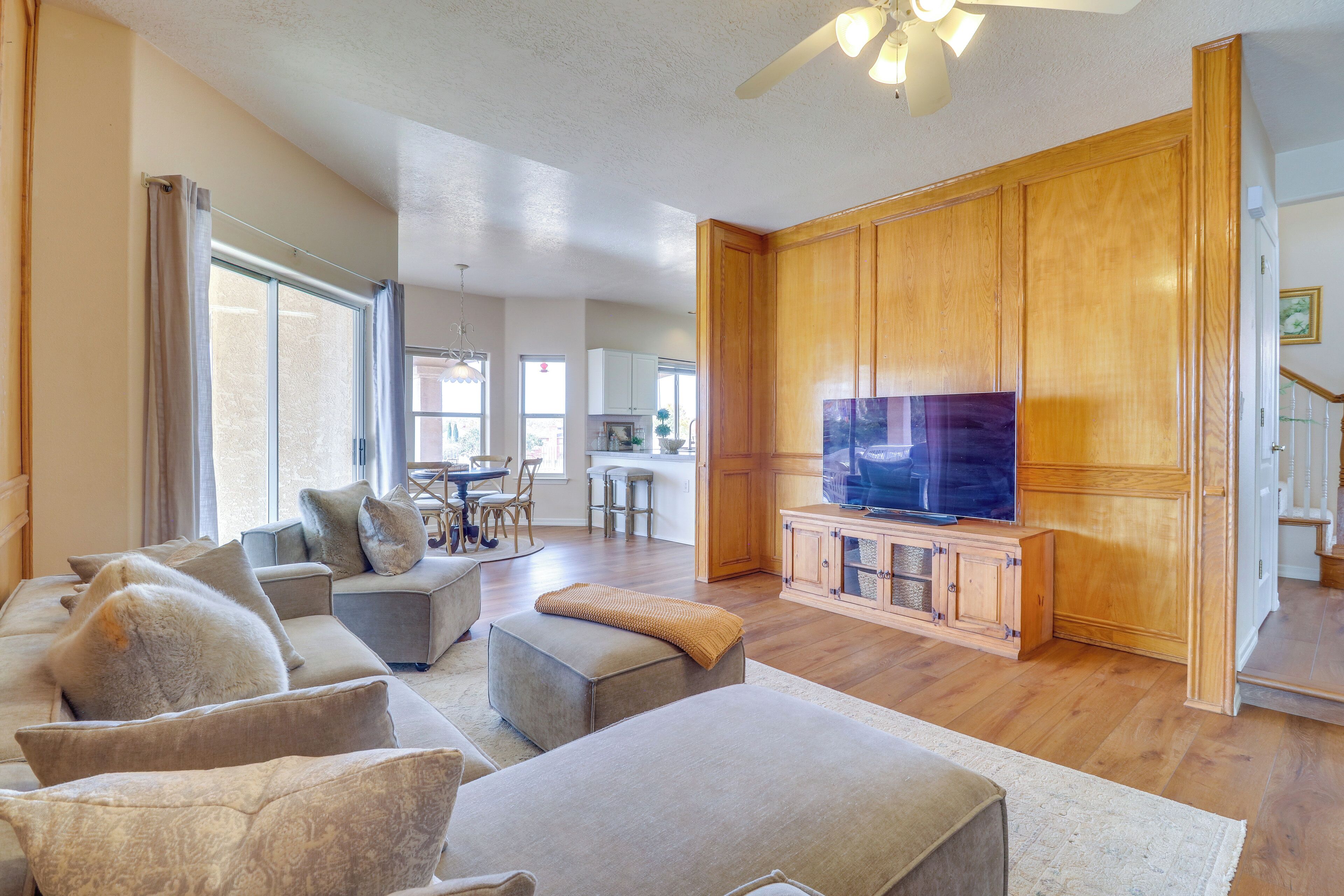 A spacious living room with a large TV, wooden cabinets, and a cozy seating area.