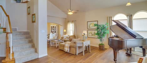 A spacious living room with a grand piano, a staircase, and a cozy seating area.