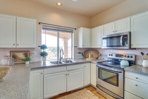 A kitchen with white cabinets, a stainless steel oven, a microwave, and a sink.