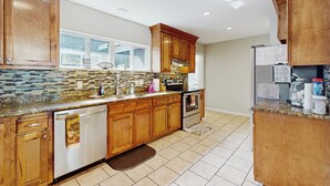 A kitchen with wooden cabinets, a granite countertop, a dishwasher, an oven, and a refrigerator. - Wine Country Retreat w/ Yard: 1 Mi to Main Street (Fredericksburg)