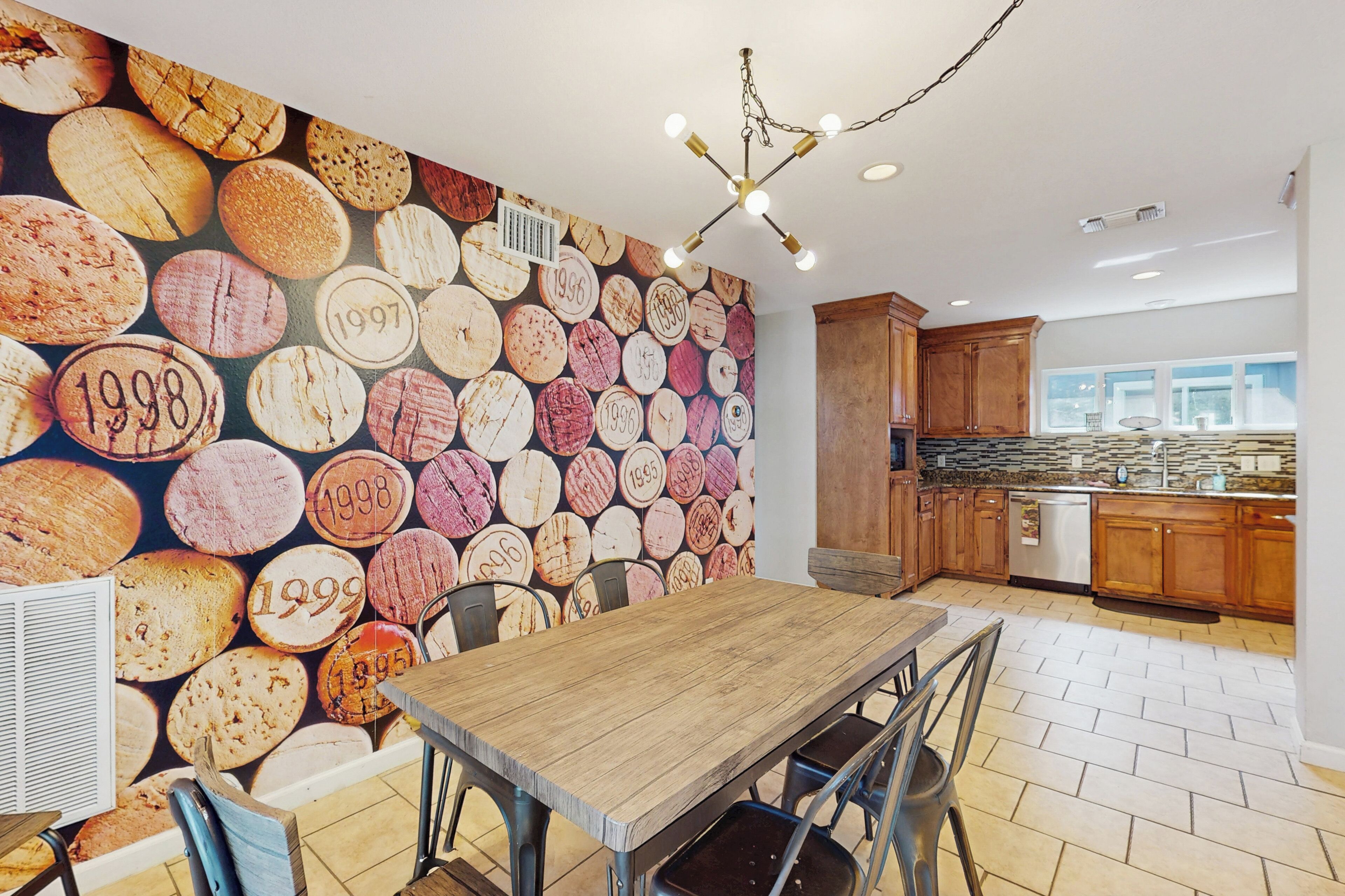 Een moderne keuken met een houten tafel en stoelen, een stenen spatwand en houten kastjes.