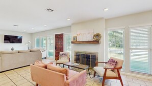 A spacious living room with a beige sofa, a pink sofa, a wooden coffee table, and a fireplace. - Wine Country Retreat w/ Yard: 1 Mi to Main Street (Fredericksburg)