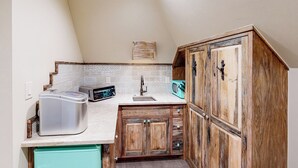 A compact kitchen with a built-in toaster, a sink, and wooden cabinets. - 'lone Star Leisure' Condo w/ Hill Country Views (Fredericksburg)
