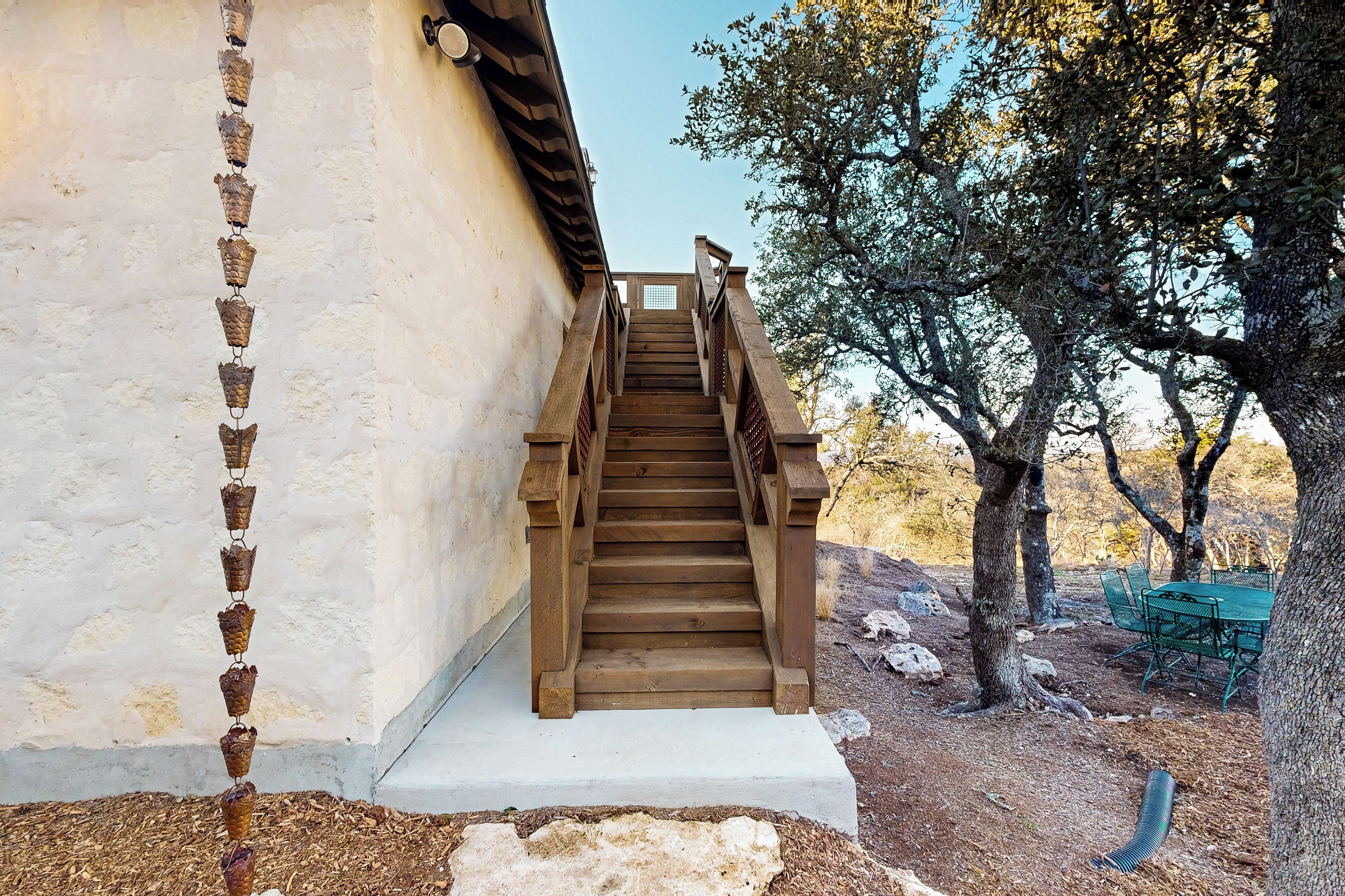 A wooden staircase leading up to a building with a white exterior wall.