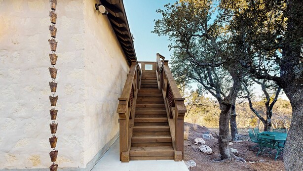 A wooden staircase leading up to a building with a white exterior wall. - 'lone Star Leisure' Condo w/ Hill Country Views (Fredericksburg)