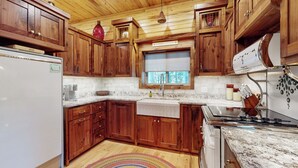 Una cocina con armarios de madera, un refrigerador blanco, un fregadero y una estufa.