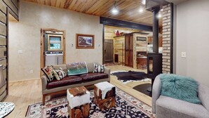 Una sala de estar acogedora con techo de madera, un sofá con cojines, una mesa de centro y una chimenea.