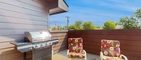 An outdoor patio with a grill and two rocking chairs.