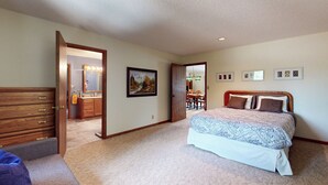 A bedroom with a bed, dresser, and a bathroom visible through an open door.