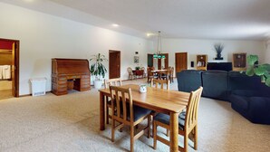 A spacious living room with a wooden dining table, chairs, a sofa, and a television.
