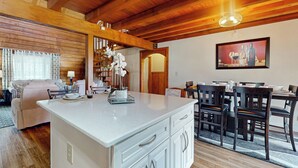 Un amplio salón con techo de madera, una mesa de comedor con sillas y una isla de cocina con armarios.