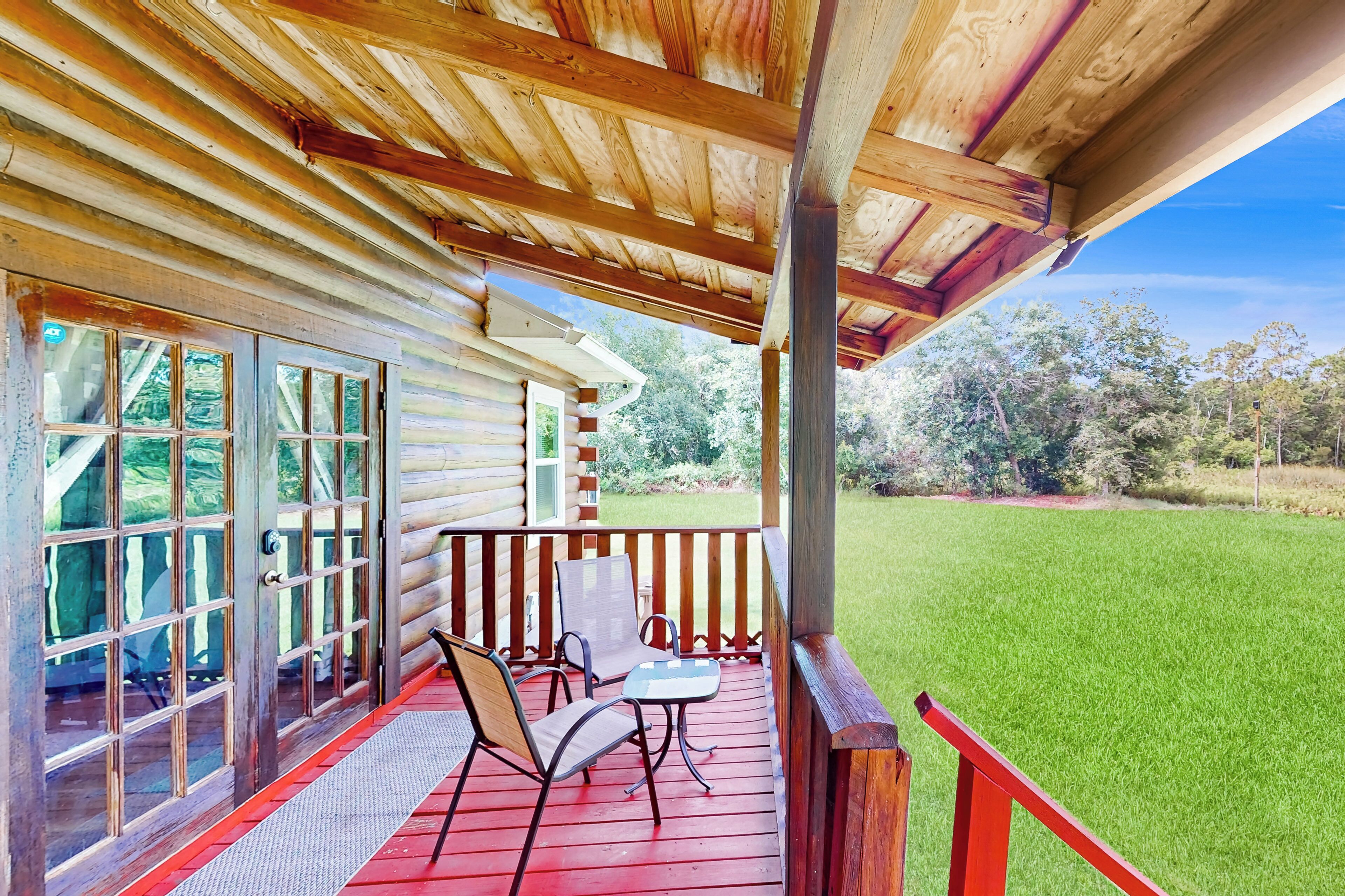 Eine Holzhütte mit Veranda, zwei Stühlen und einem Tisch.