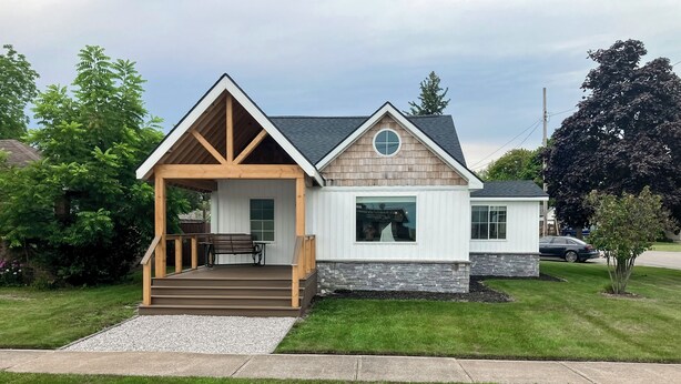 A two-story house with a covered porch, a stone foundation, and a well-maintained lawn. - Walk to Downtown & Beach! Water-view Home (East Tawas)