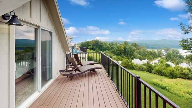 A balcony with a wooden deck, two lounge chairs, and a glass door leading to a room. - 3 BR Home w/ Decks & Lake Views! (La Follette)