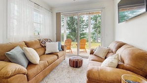 A living room with two brown leather sofas, a round ottoman, and a ceiling fan. - 3 BR Home w/ Decks & Lake Views! (La Follette)