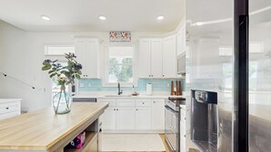 A modern kitchen with white cabinets, a wooden countertop, a stainless steel refrigerator, and a window with blinds. - 3 BR Home w/ Decks & Lake Views! (La Follette)