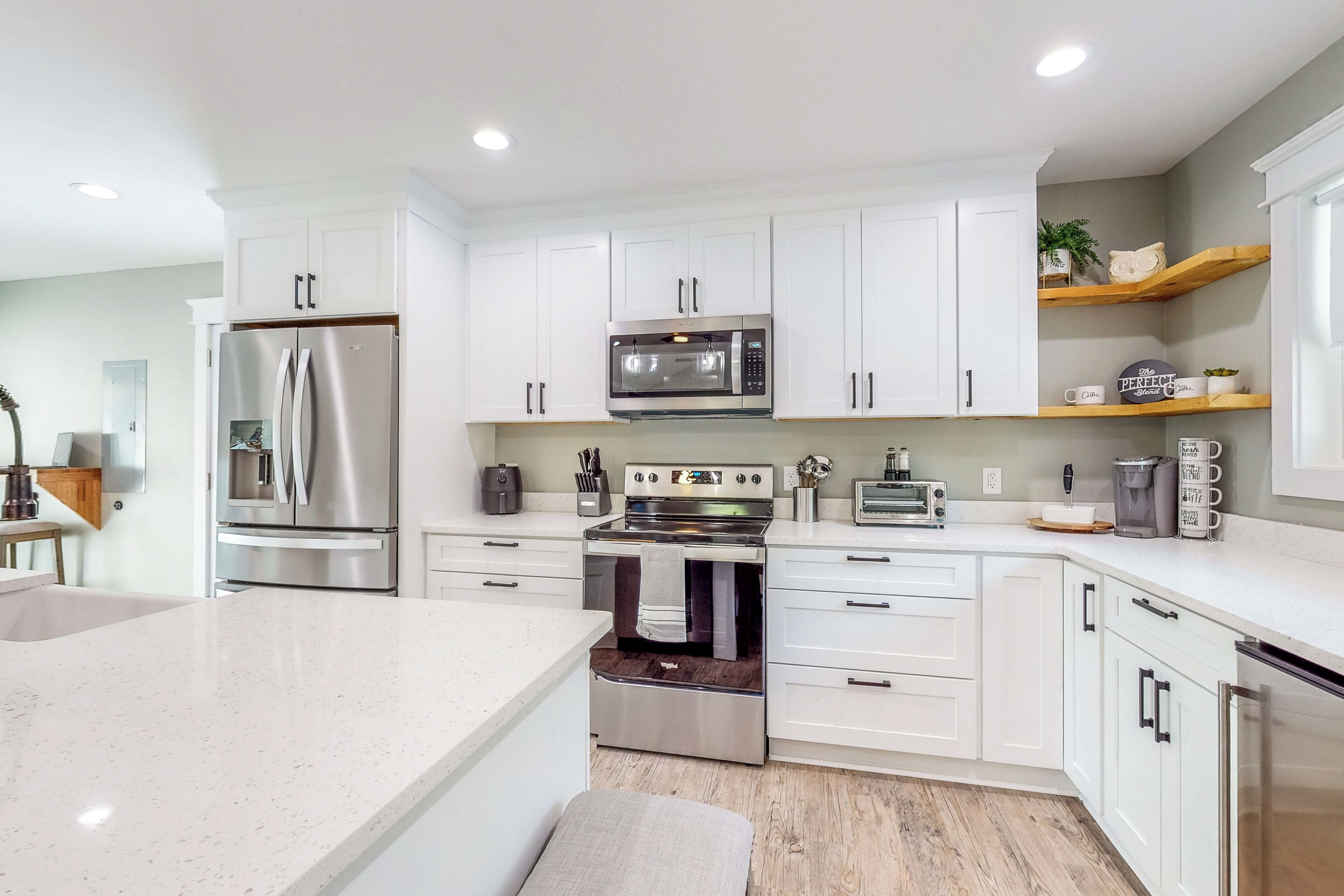 A modern kitchen with white cabinets, stainless steel appliances, and a wooden countertop.