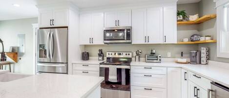 A modern kitchen with white cabinets, stainless steel appliances, and a wooden countertop.