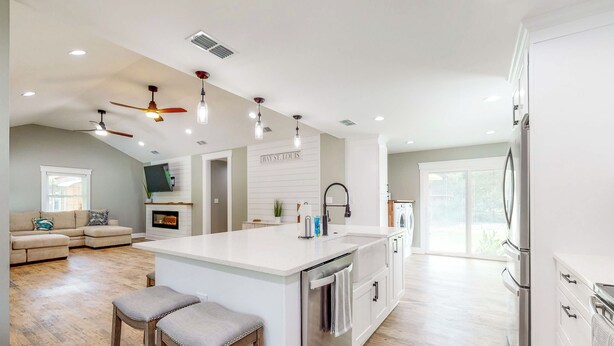 Una cocina amplia con una isla central, electrodomésticos modernos y una zona de comedor con taburetes de bar.