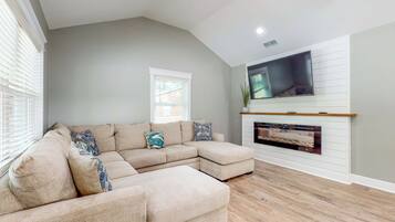 A living room with a sectional sofa, a fireplace, and a mounted TV.