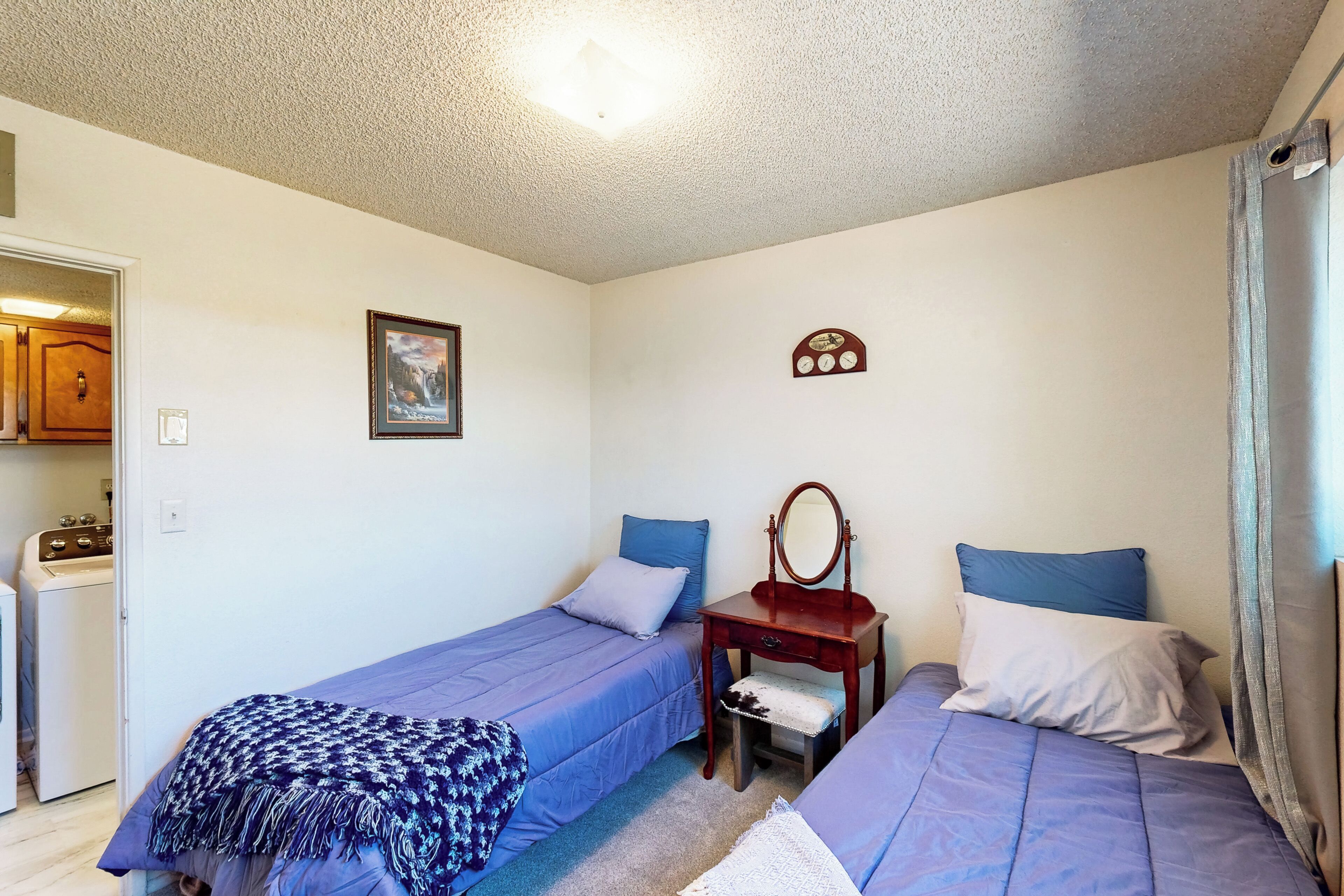 A bedroom with two beds, a dresser, a mirror, and a wall clock.