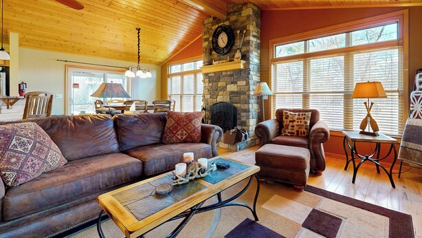 A cozy living room with a stone fireplace, leather sofas, and a wooden ceiling. - Pool & Beach Access! 'lake Arrowhead Hideaway' (Nekoosa)