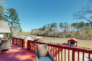 A wooden deck with wicker furniture and a view of a lake surrounded by trees.