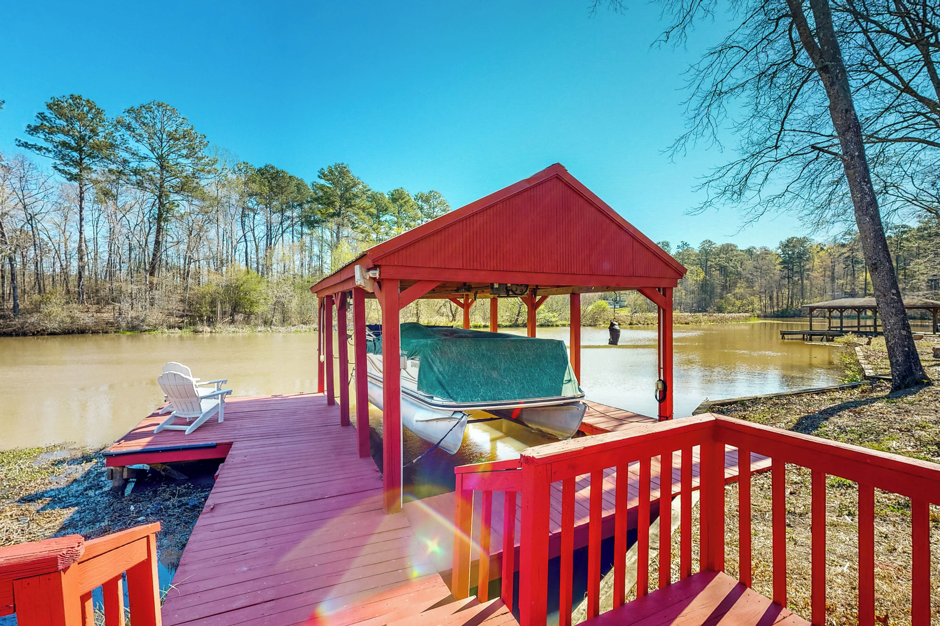 A wooden dock with a red gazebo, a boat, and a chair.
