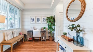 A cozy room with a wooden bench, a desk, a chair, a large mirror, and framed botanical prints on the wall. - Overlooking 10th Fairway 2 Free Rounds of Golf (Naples)