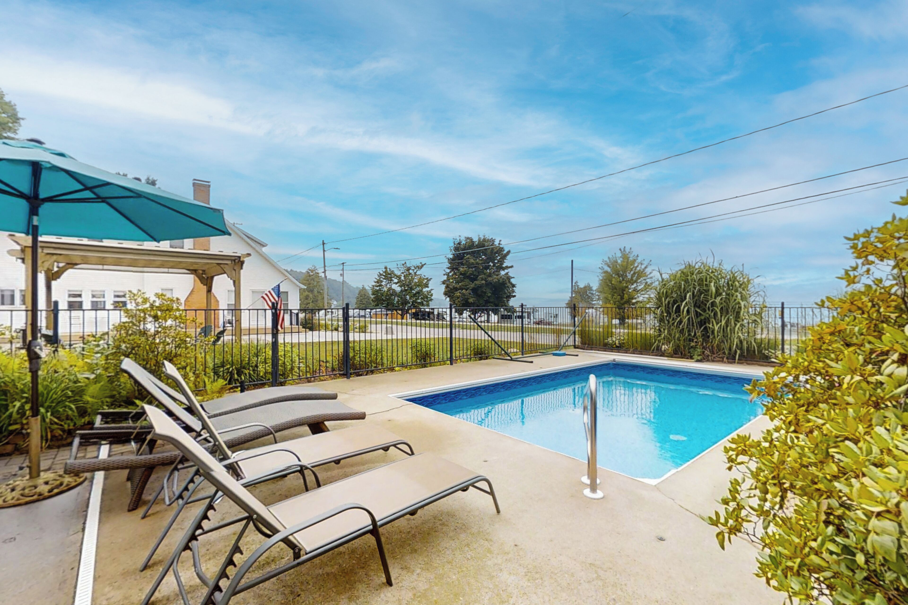 Ein Swimmingpool mit Liegestühlen und einer überdachten Sitzgelegenheit.