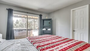A bedroom with a bed, a window with curtains, a door, and a small cabinet. - Private Hot Tub, 4 Mi to Usafa: Cozy Apartment! (Colorado Springs)