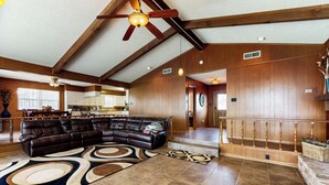 A spacious living area with a large sectional sofa, a wooden ceiling, and a staircase leading to an upper level. - Laid-back Lake House' w/ Wraparound Deck (Kemp)