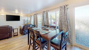A dining area with a wooden table, four chairs, and a TV mounted on the wall. - Soft Sunsets & Still Water at Flathead Condo (Polson)