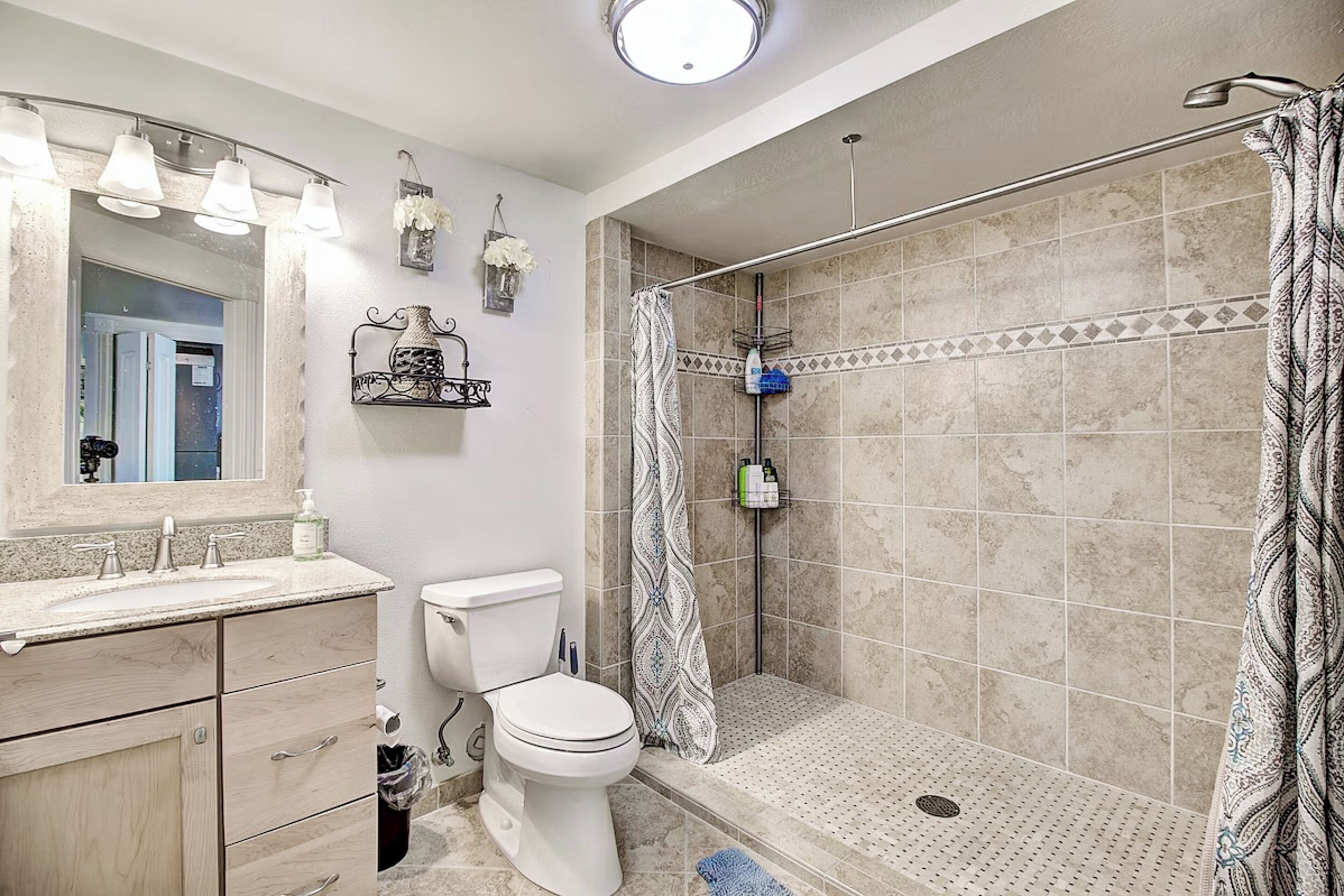 A bathroom with a shower, toilet, sink, and vanity.