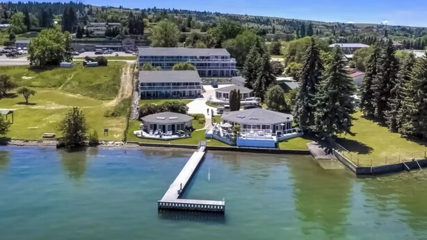 A lakeside property with a dock, buildings, and surrounding greenery. - Soft Sunsets & Still Water at Flathead Condo (Polson)