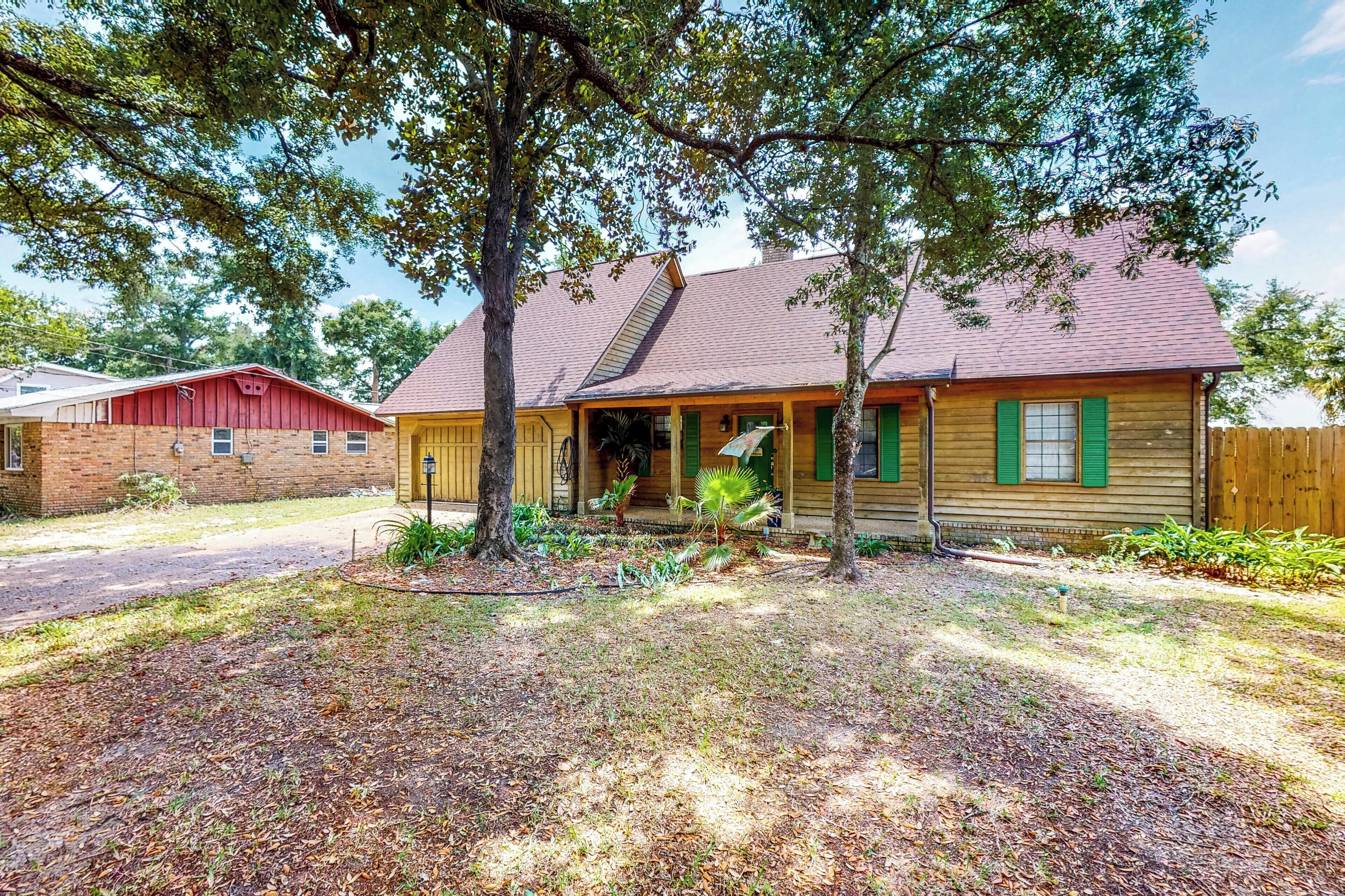 A two-story house with a front porch, a brick garage, and a wooden fence.