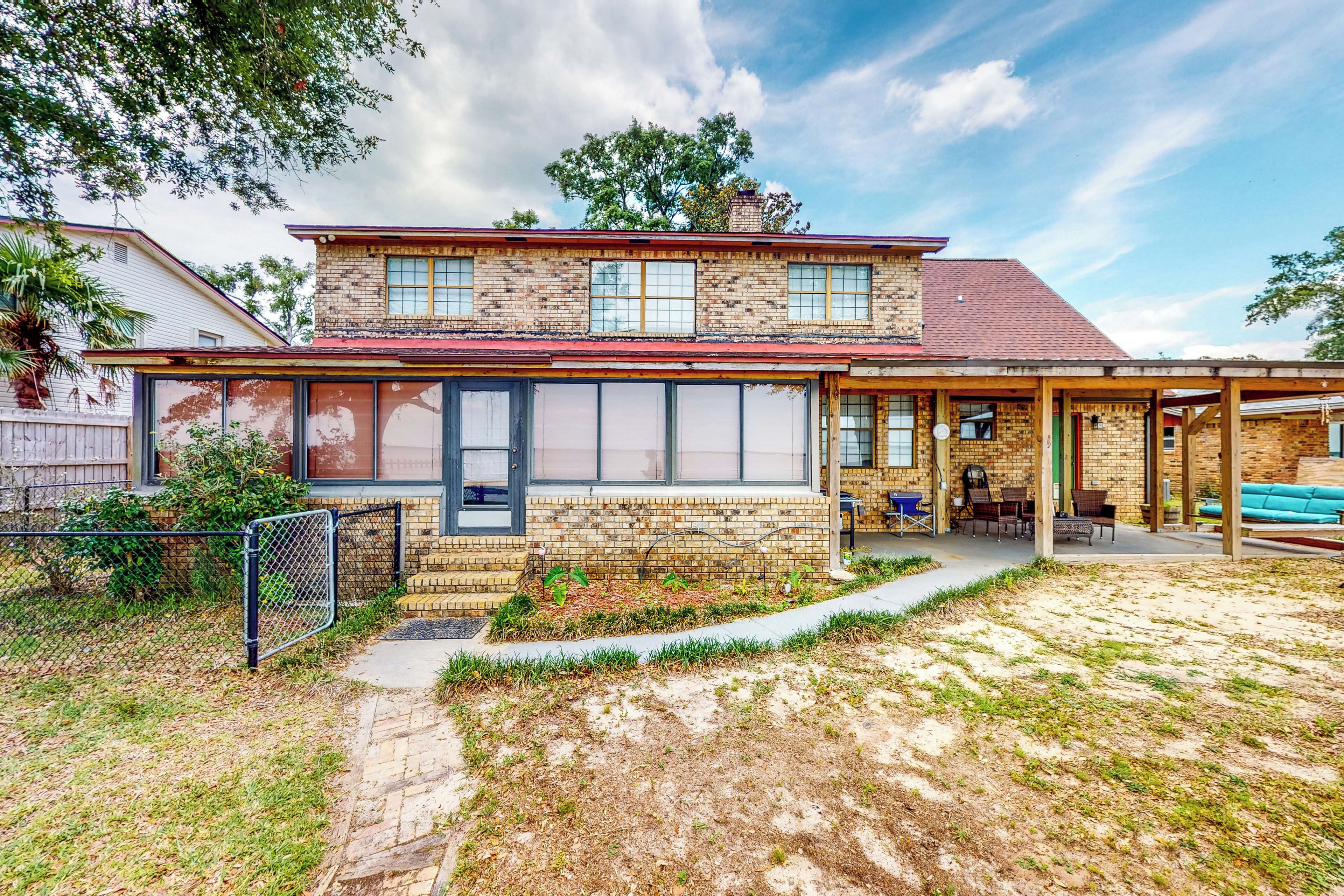 A two-story house with a brick exterior, a covered porch, and a front yard with a pathway.