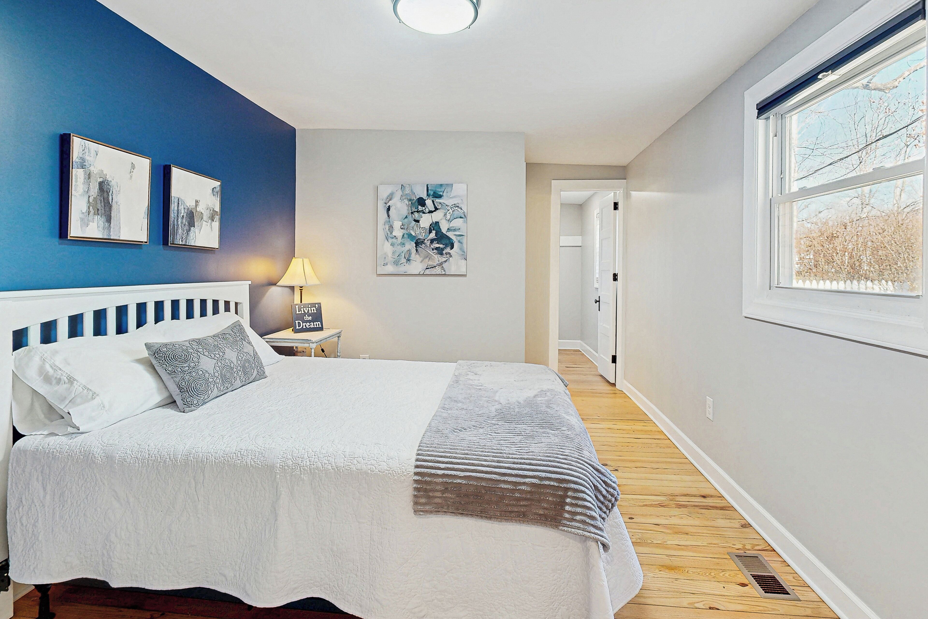 A bedroom with a bed, a nightstand, a lamp, and artwork on the walls.