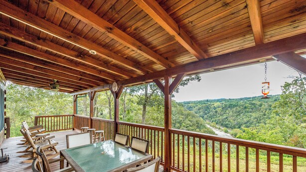 A wooden deck with a glass-top table and chairs, overlooking a valley. - 3BR Water View, Hot Tub, Fireplace & Balcony (Marshall)